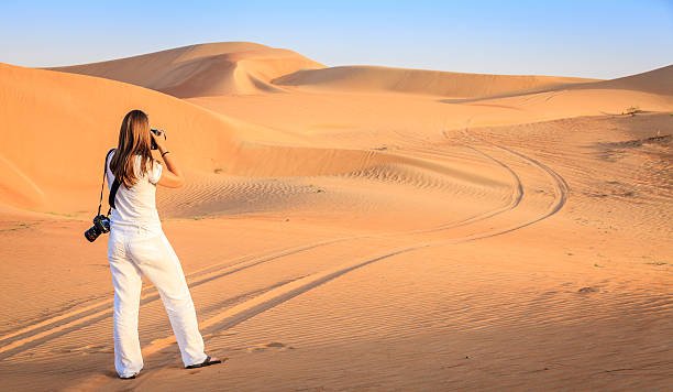 A woman is taking photos of dunes in Desert Conservation area near Dubai, UAE